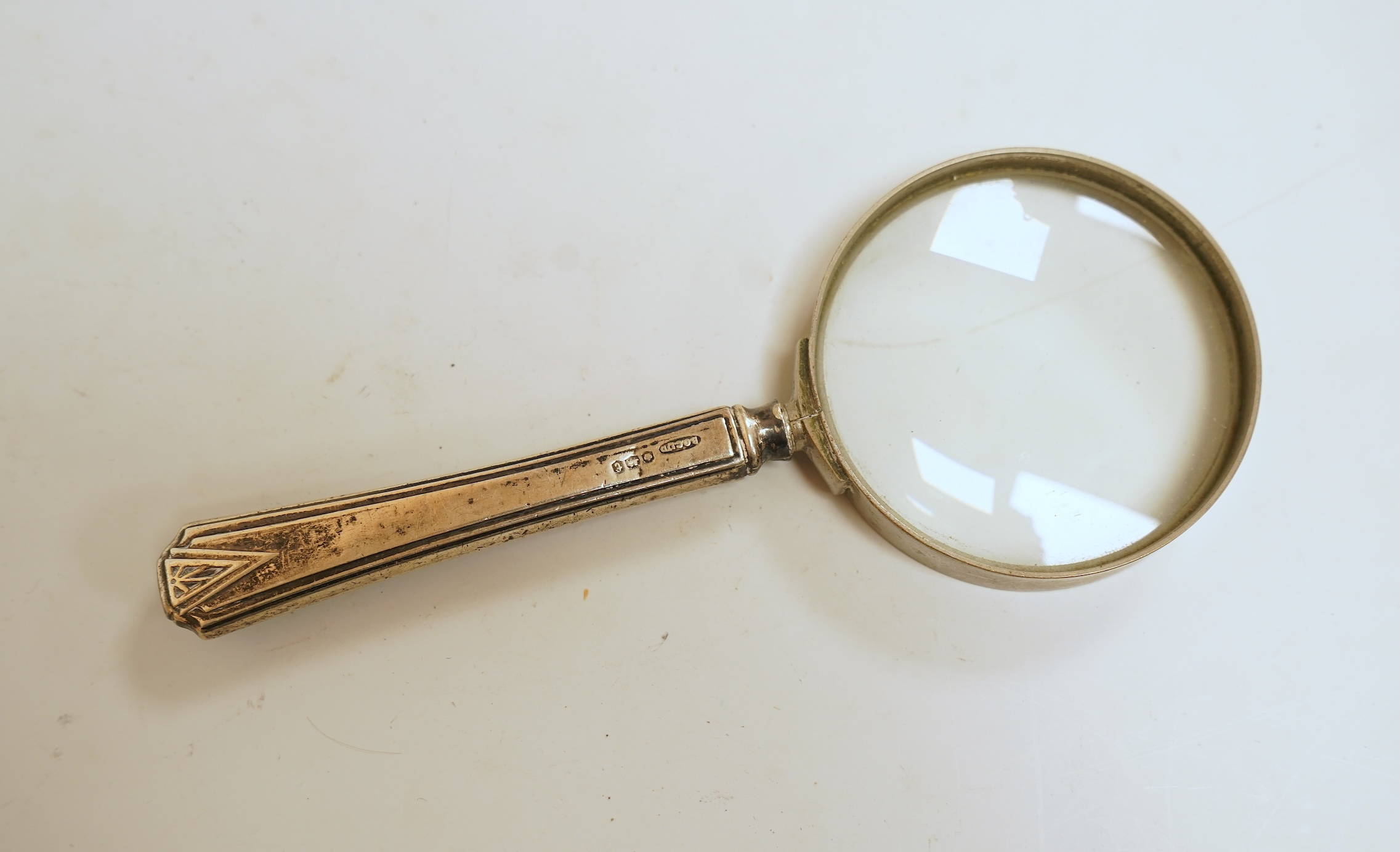 A small silver mounted capstan inkwell, a set of four George V engine turned silver napkin rings and a silver handled magnifying glass.